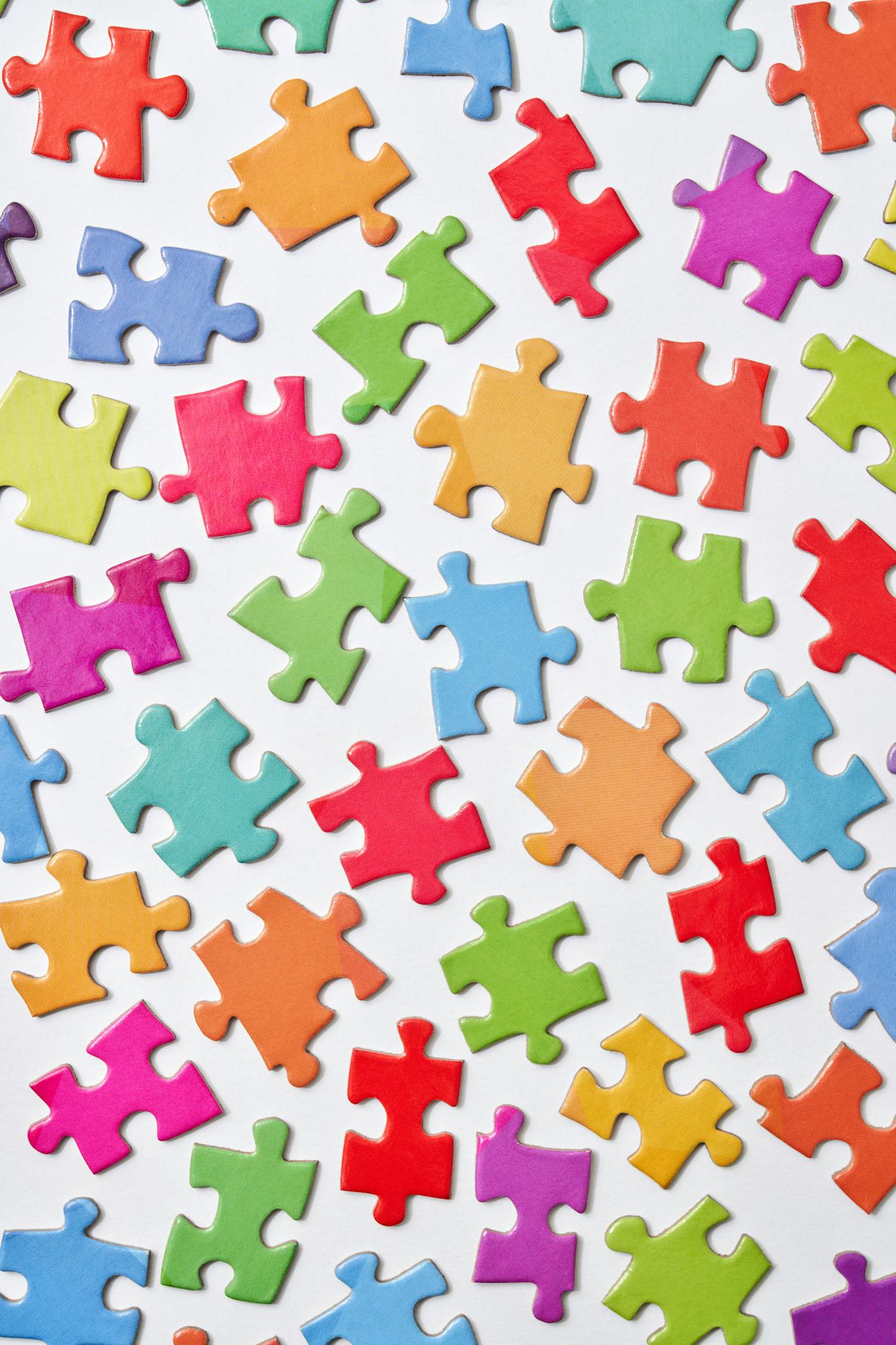 A vibrant collection of colorful jigsaw puzzle pieces scattered on a white background.